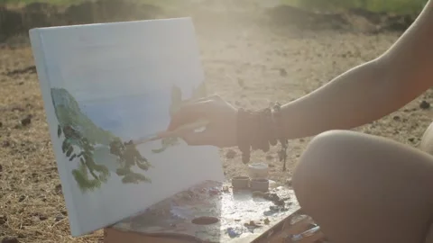 Close up side view of female hands painting picture landscape outdoors backlit Stock Footage 132341422