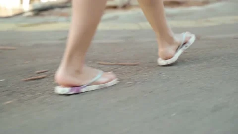Close-up side view on female legs in flip-flops. a woman walks along the Stock Footage 200242744