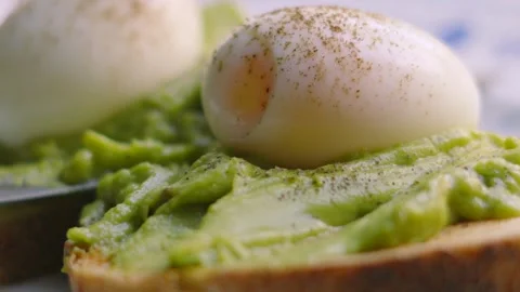 Close-up Side View of Fresh Soft Boiled Eggs with Smashed Avocado on Sourdough Stock Footage 341605730