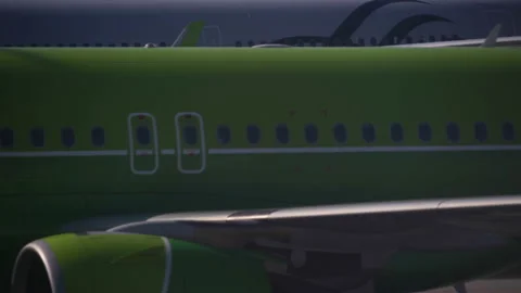 Close up side view a green plane is moving along the runway and behind it the Stock Footage 134577257