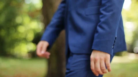 Close up side view of groom in blue suit walking on nature at sunny day Stock Footage 66004265
