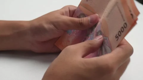 Close up side view of hands counting money Indonesian rupiah 库存影片 276519127