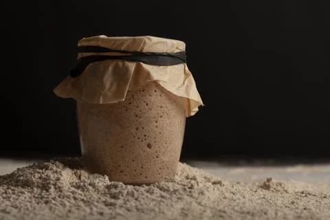 Close up side view image of glass cup of sourdough starter culture with bubbles Stock Photos