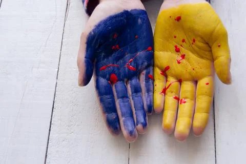 Close up side view image of two female hands painted in Ukrainian blue and ye 写真素材