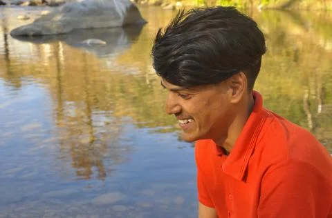 Close up of side view of an Indian young guy smiling with looking sideways Stock Photos
