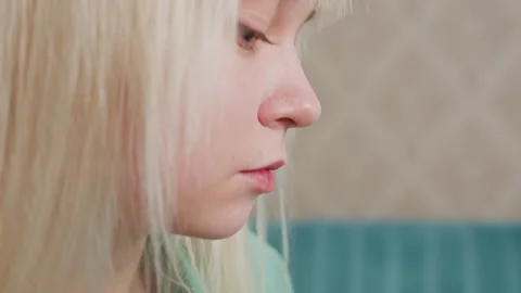 Close up side view of lady eating popcorn with patterned wall and green couch Stock Footage 314934535