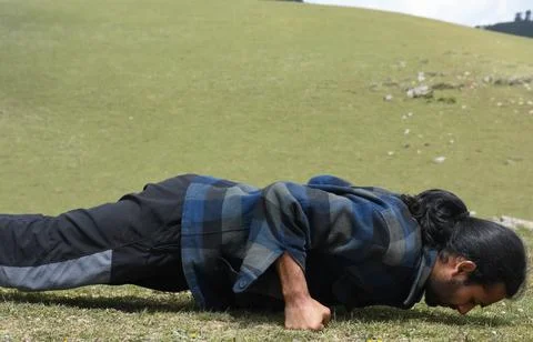 Close-up side view of a long haired Indian young guy doing fist push ups  Stock Photos