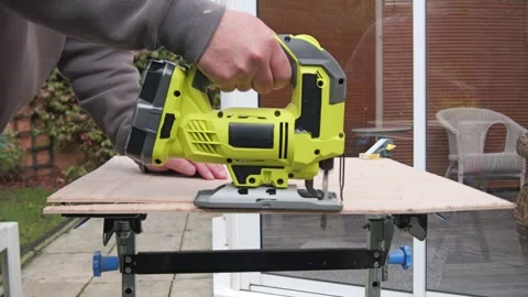 Close Up side view of a man using a battery powered Jigsaw cutting a board .. Stock Footage 321001702