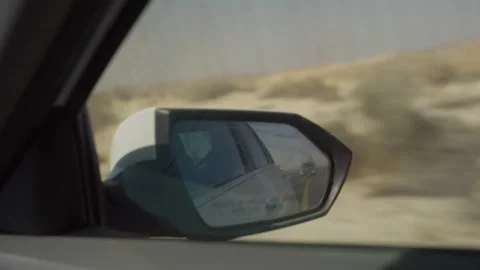 Close up on side view mirror or wing mirror as car driving on desert road Stock Footage 313904348
