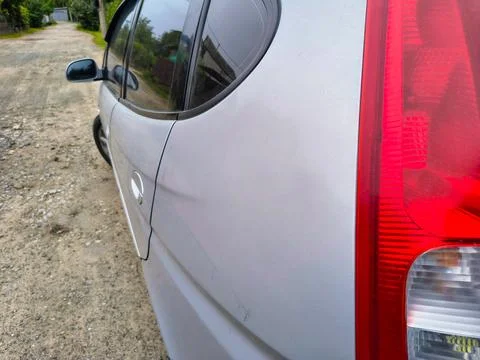 Close-up side view of a parked silver car on a rural dirt road. Focus on tint 스톡 사진