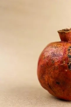 Close-up side view of a partially visible pomegranate placed against a smooth Stock Photos