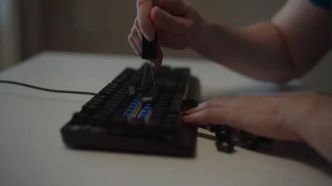 Close-up side view of person using keycap puller tool to remove keys from Stock Footage 342759348