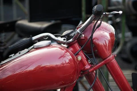 Close up side view of red vintage motorcycle fuel tank and handlebar assembly Stock Photos