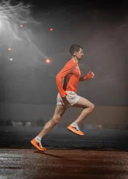 Close side view of a runner under a hazy floodlight at night 写真素材