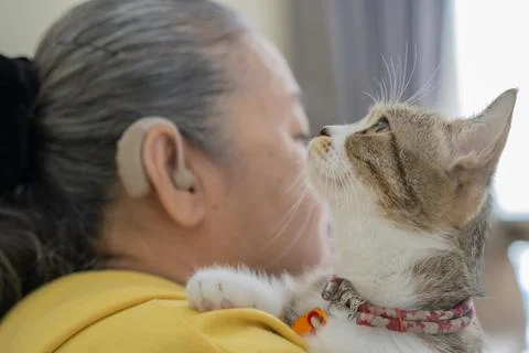 Close-up side view of a senior elderly woman with hearing aid holding her c.. Stock Photos
