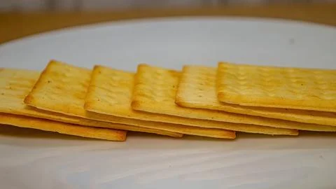 A close up side view of several golden, rectangular crackers arranged in a .. Foto stock