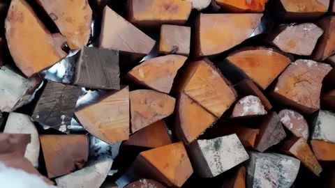 Close-up side view of split firewood stacked under a shed roof with snow and Stock Footage 327689897