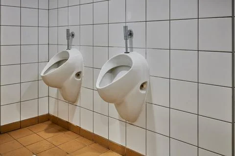 Close up side view of two white ceramic urinals in a clean public restroom wi Stockfoto's