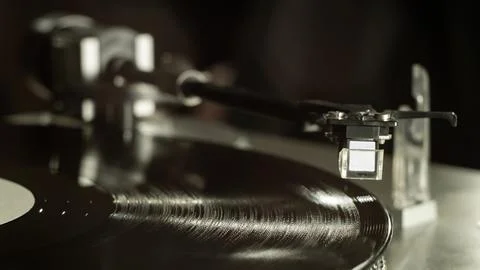 Close up side view of vinyl record spinning on turntable player with tonearm  Stock Photos