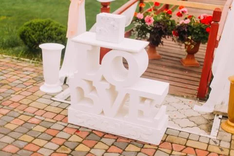 The close-up side view of the white signs love placed near the flowers. Stock Photos