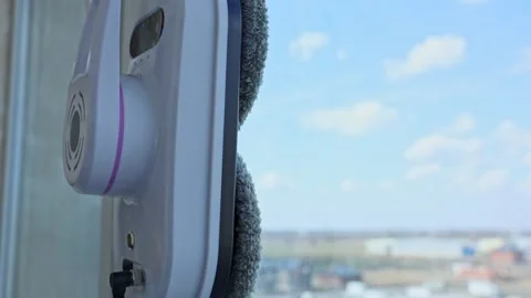 A close-up side view of a window cleaner robot moving across the glass moving Stock Footage 307170142