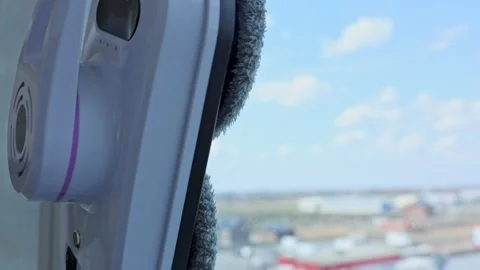 A close-up side view of a window cleaner robot moving across the glass moving Stock Footage 307170653