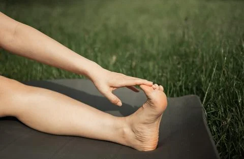 Close up side view young barefoot woman sitting on yoga mat Foto stock