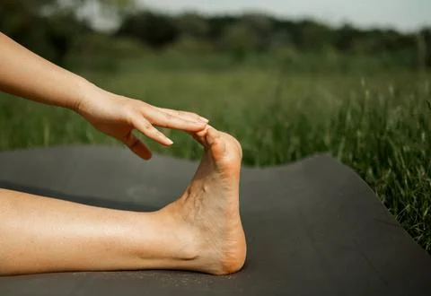 Close up side view young barefoot woman sitting on yoga mat Foto stock