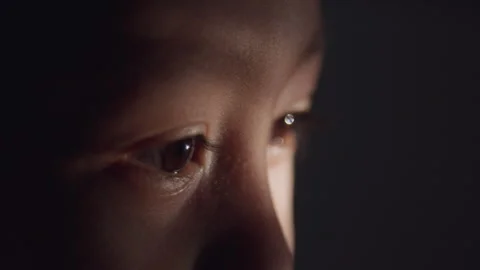 Close-up side view of a young boy's brown eye illuminated by soft light Stock Footage 340595402