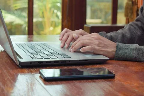 Close up side view young man typing with laptop on table in livingroom, remote Stock Photos