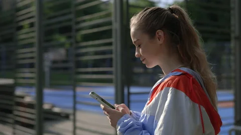 Close side view of the young smiled woman going and texting in her phone holding Stock Footage 214928410