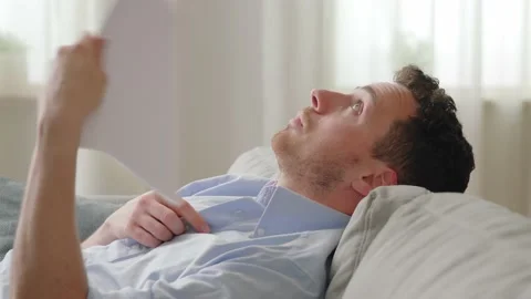 Close up side view young sweaty man lean on sofa cooling himself with fan waver Stock Footage 169017632