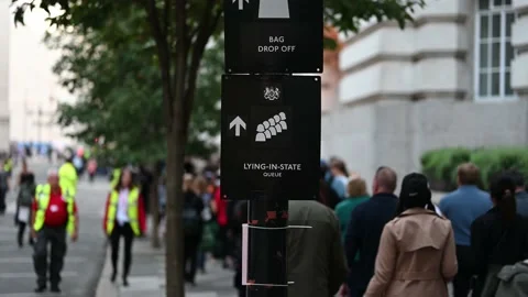 Close up of a sign for the Queen's Lying in State with a large queue of people Stock Footage 210523478