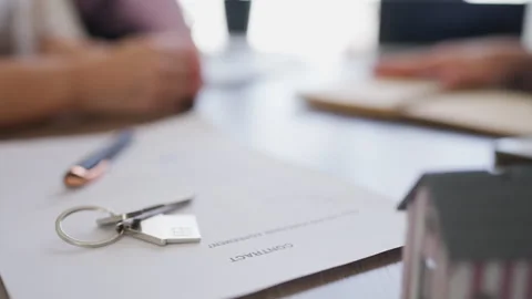 Close-up on a signed real estate contract, house keys, and a miniature home.. Stock Footage 341755176