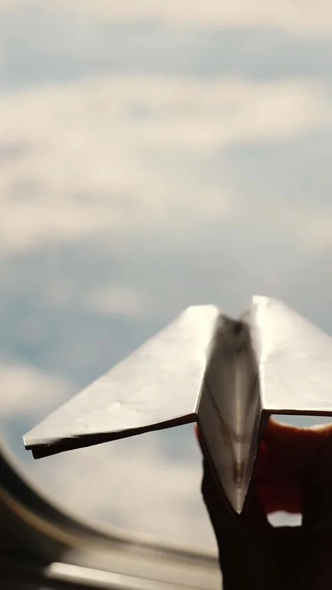 Close-up. Silhouette of a child's hand with small paper plane against the Stock Footage 313800283