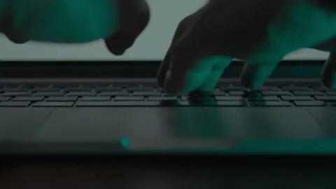 A close-up silhouette of hands typing on a laptop keyboard Stock Footage 333958476