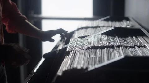 Close-up silhouette of a man sifting through a row of vinyl records Video stock 122594577