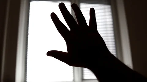 Close-up silhouette of a man's hand reaching for the light. Stock Footage 129904701