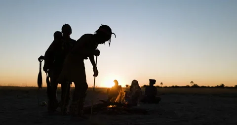 Close-up silhouette view of a small group of Bushmen doing a traditional dance Vídeo Stock 155435618