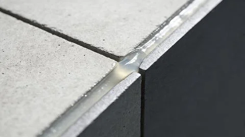 Close-up of silicone sealant applied along tile and window joints. Detail of sea Фото