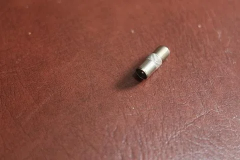 Close-up of a silver coaxial cable connector lying on a textured surface Stock Photos