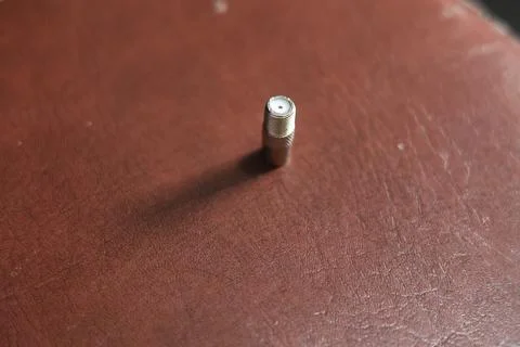 Close-up of a silver coaxial cable connector lying on a textured surface Stock Photos