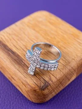 Close-up of a silver cross-shaped ring with white rhinestones  against a wood Stock Photos