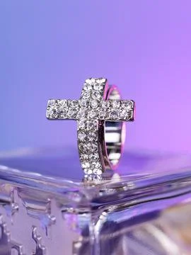 Close-up of a silver cross-shaped ring with white rhinestones on a white mann Stock Photos