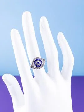 Close-up of a silver eye-shaped ring with white and blue rhinestones on a whi Stock Photos