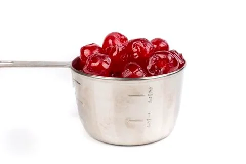 Close up silver measuring cup containing maraschino cherries Foto stock