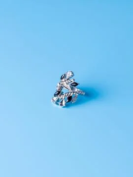 Close-up of a silver ring with white and black  stones against a blue backgro Stock Photos