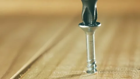 Close-up silver self tapping screw unscrewing from wood board. Macro view Stock Footage 312604133