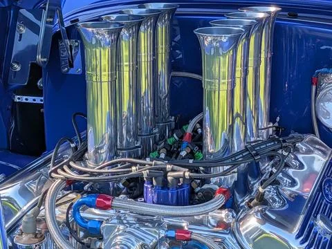 Close-up of a silver V8 engine with eight chrome tubes protruding from the block Stock Photos