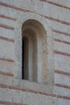 A close-up of a simple but stylish stone arched window set in the side of an Stock Photos